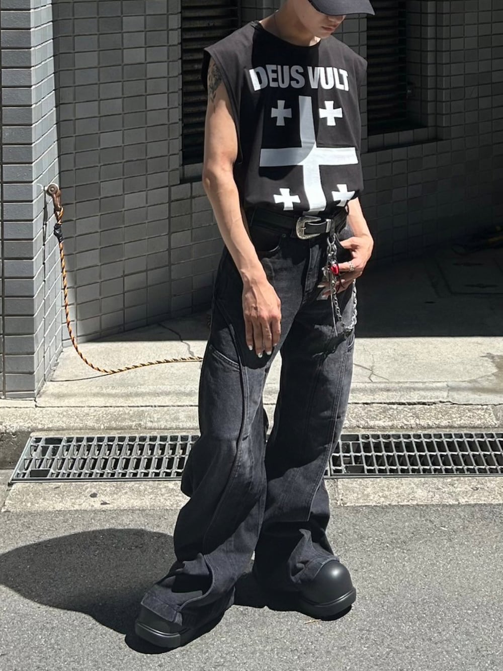 ブラック系のデニムパンツ、ブラック系のスリッポン、ブラック系のキャップを着用したメンズの夏コーディネートの1枚目の写真