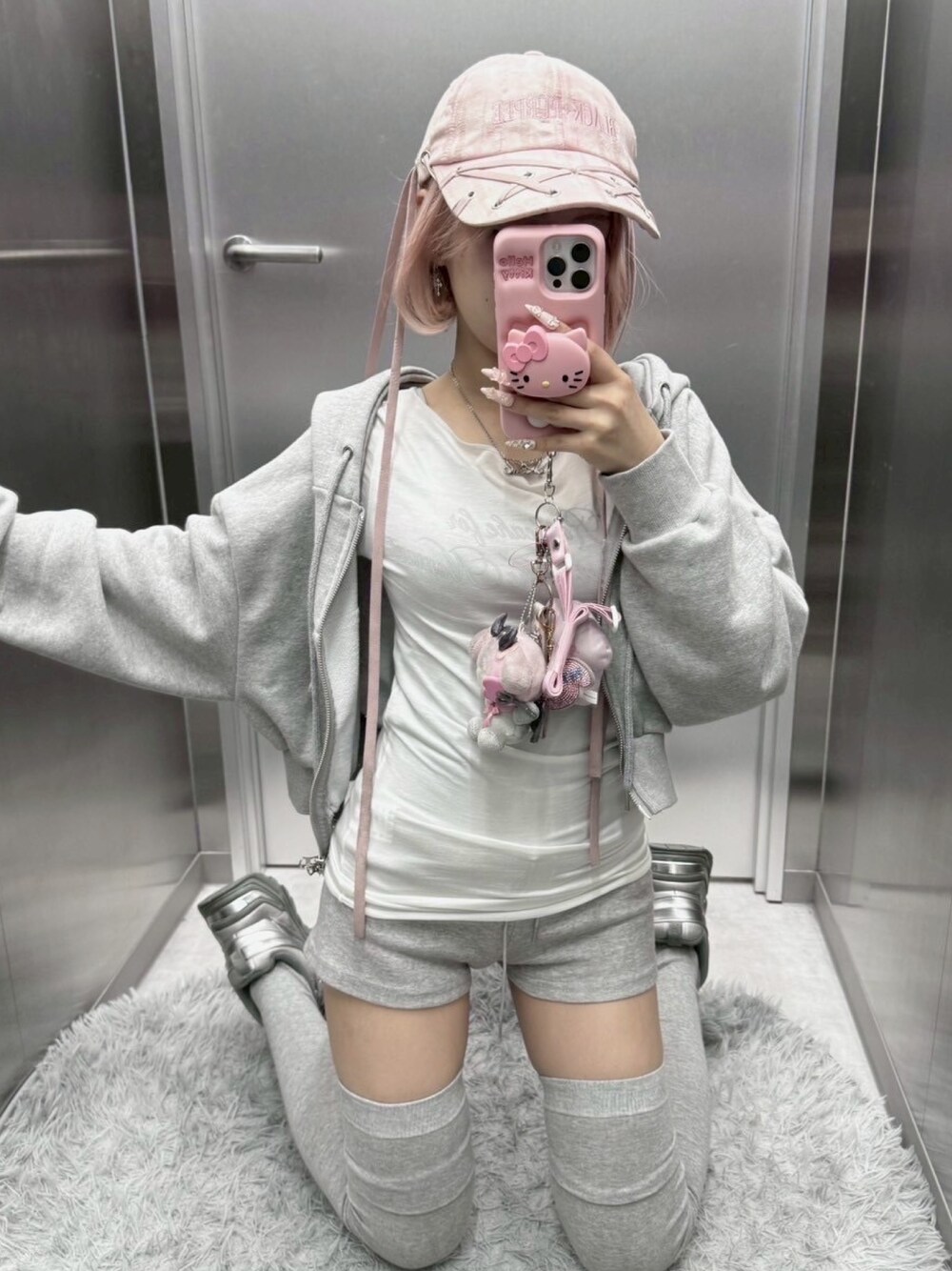 グレー系のスウェットパンツ、ピンク系のキャップを着用したレディースの秋コーディネートの1枚目の写真