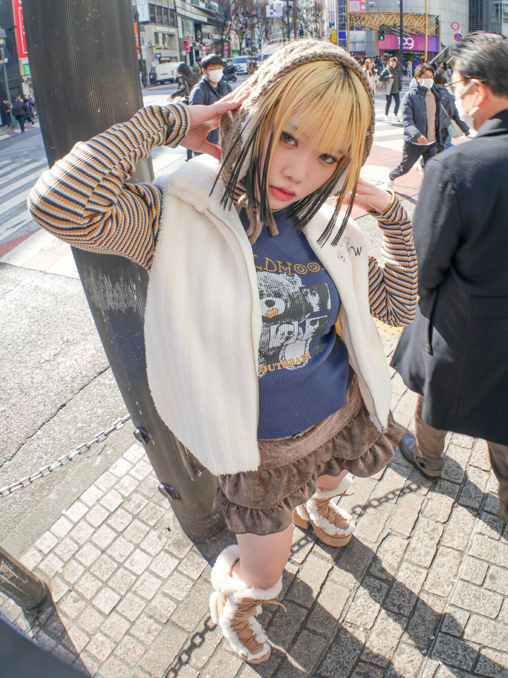 ホワイト系のダウンベスト、ブルー系のTシャツ/カットソー、ブラウン系のスカートを着用したレディースの冬コーディネートの1枚目の写真