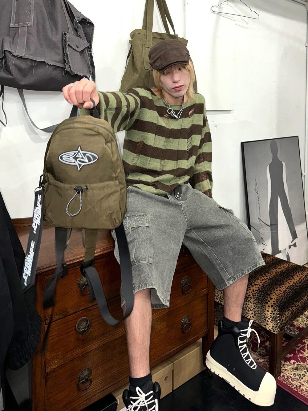 グリーン系のバックパック/リュック、グリーン系のニット/セーター、グレー系のデニムパンツを着用したメンズの冬コーディネートの1枚目の写真