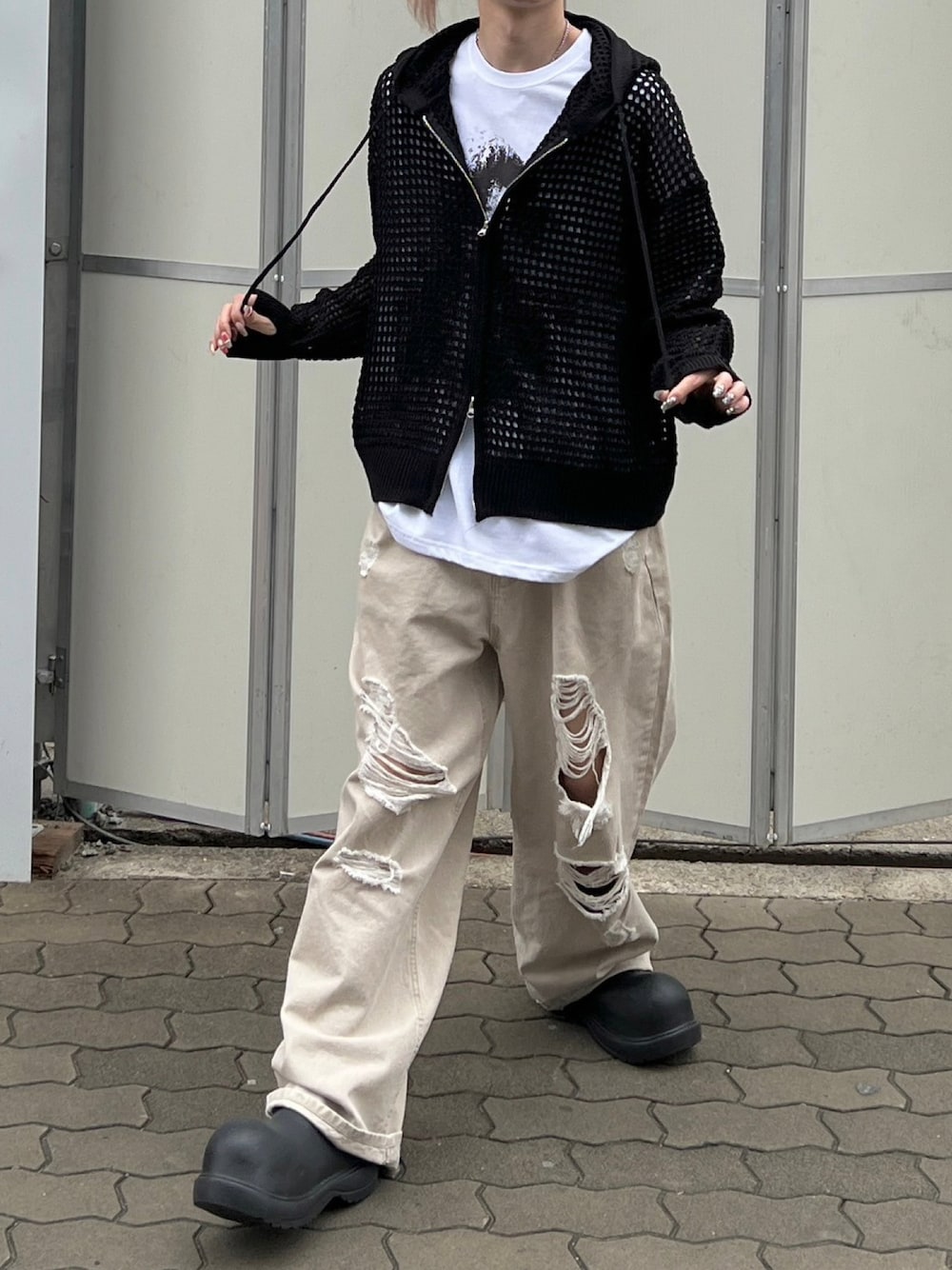ブラック系のパーカー、ブラック系のスリッポン、ベージュ系のデニムパンツを着用したメンズの春コーディネートの1枚目の写真