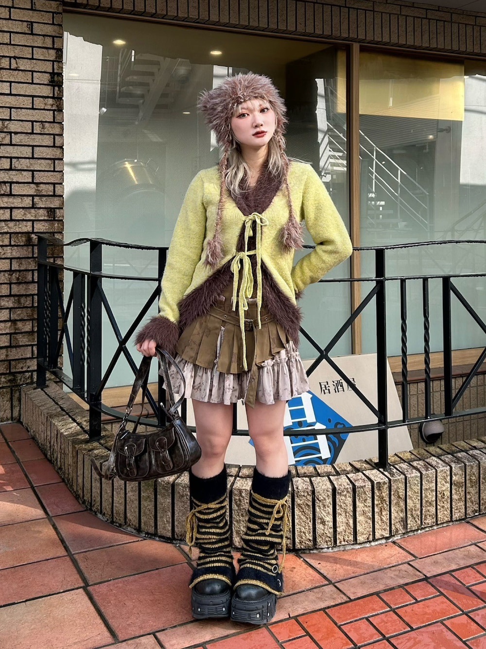 グリーン系のスカート、ブラウン系のショルダーバッグ、ブラウン系のニットキャップ/ビーニーを着用したレディースの冬コーディネートの1枚目の写真