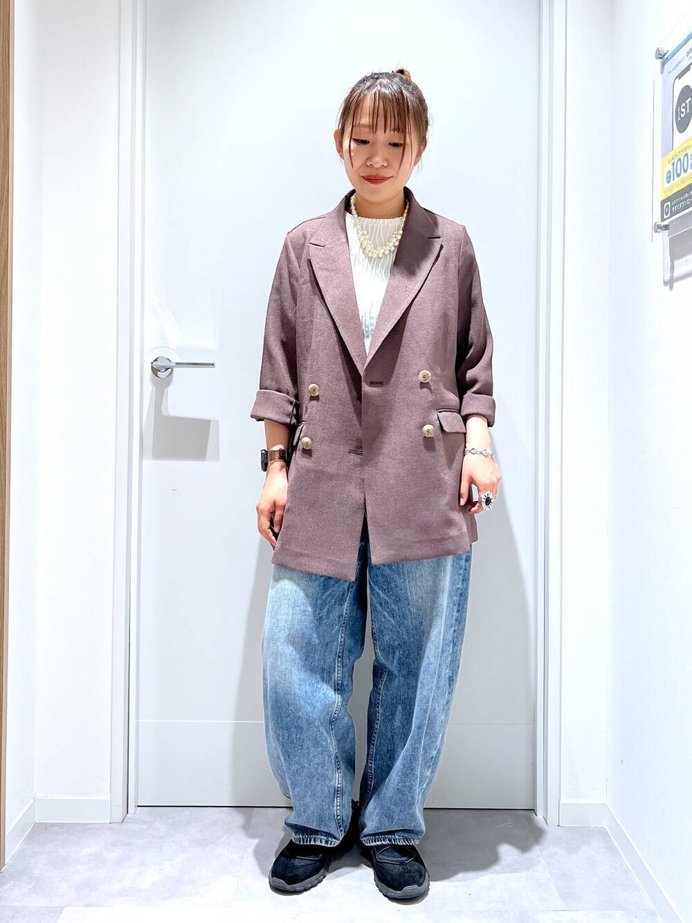 ブルー系のデニムパンツ、ブラウン系のテーラードジャケット、ブラック系のスニーカーを着用したレディースの春コーディネートの1枚目の写真