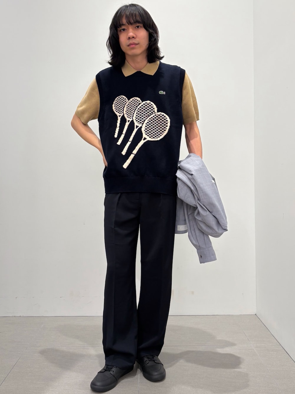 ブラック系のベスト、ブルー系のスラックス、ブラック系のスニーカーを着用したメンズの春コーディネートの1枚目の写真