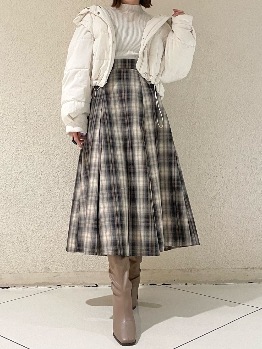 ホワイト系のニット/セーター、ホワイト系のダウンジャケット/コート、ブラウン系のスカートを着用したレディースの冬コーディネートの1枚目の写真