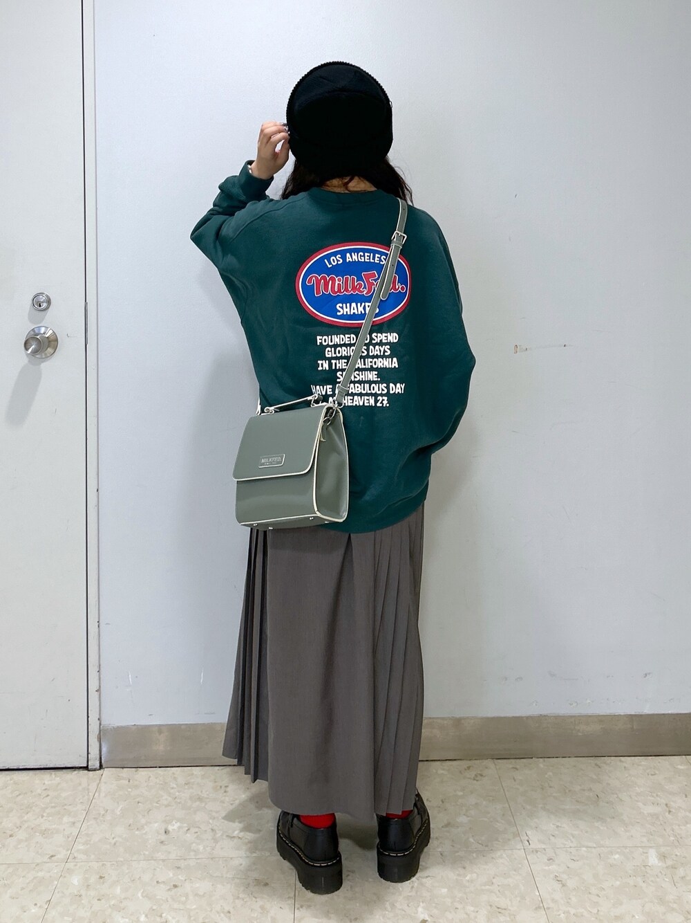 グレー系のショルダーバッグ、グリーン系のスウェット、ブラック系のローファーを着用したレディースの冬コーディネートの1枚目の写真