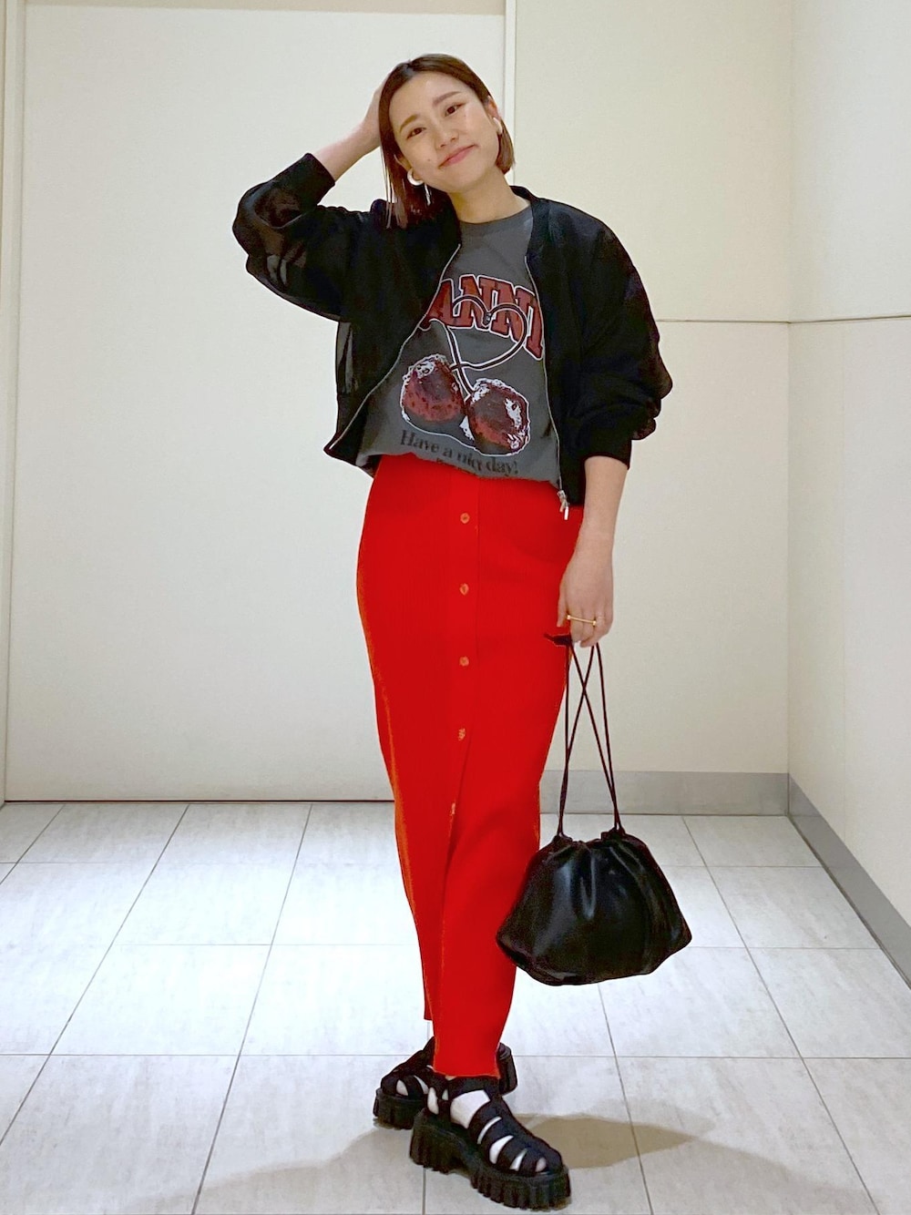 ブラック系のサンダル、ブラック系のショルダーバッグ、レッド系のスカートを着用したレディースの春コーディネートの1枚目の写真