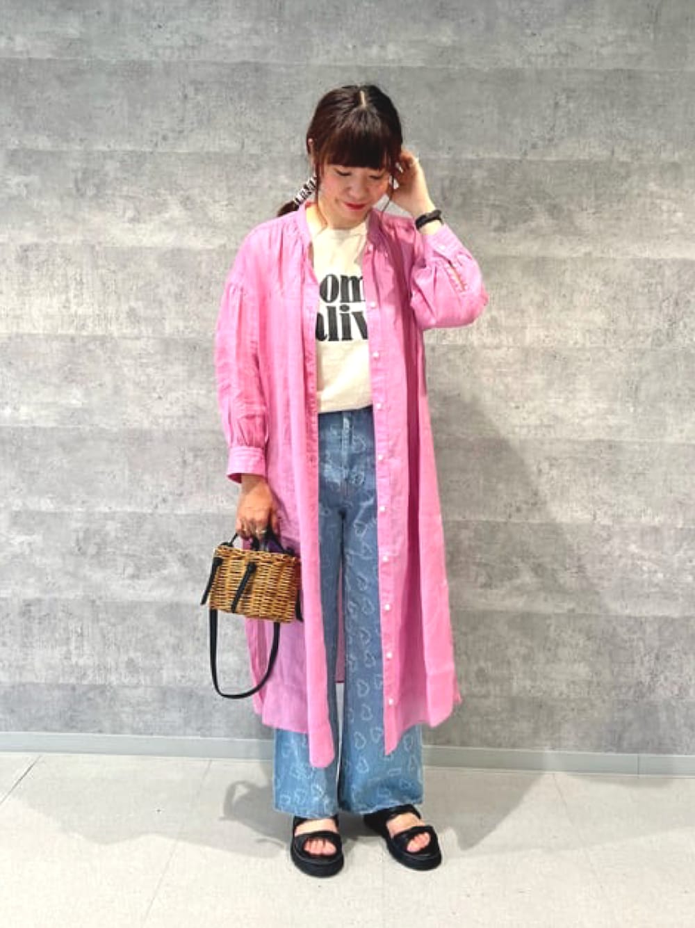 ピンク系のシャツワンピース、ブルー系のデニムパンツ、ブラック系のサンダルを着用したレディースの春コーディネートの1枚目の写真