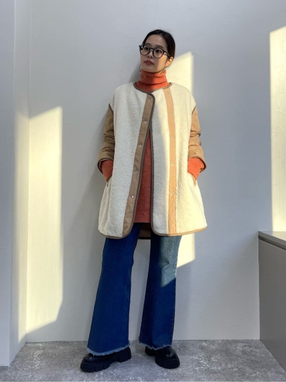 オレンジ系のニット/セーター、ブルー系のデニムパンツ、ホワイト系のその他アウターを着用したレディースの冬コーディネートの1枚目の写真