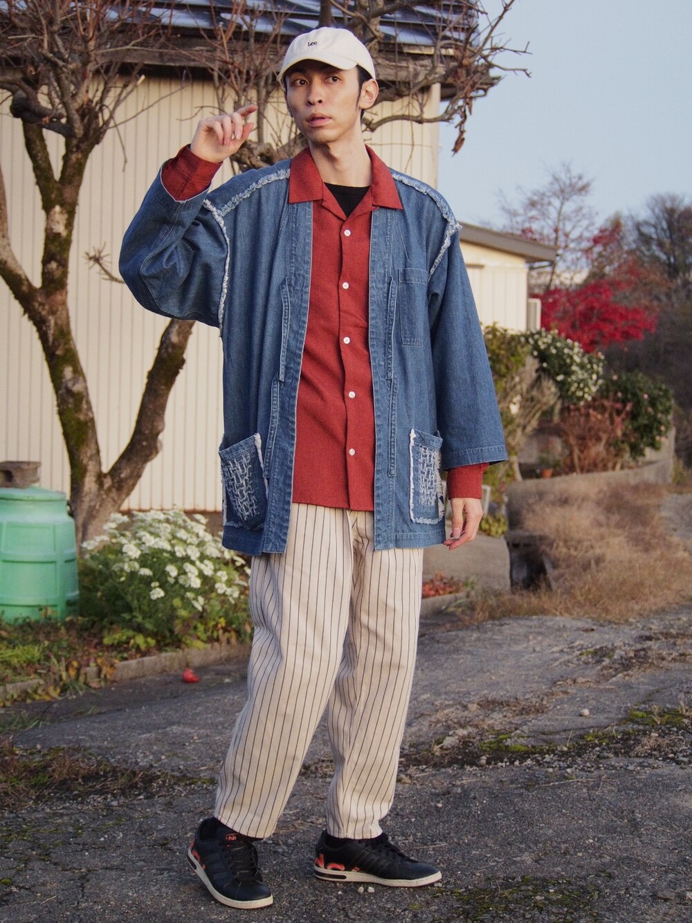 ベージュ系のパンツ、ブラック系のスニーカー、オレンジ系のシャツ/ブラウスを着用したメンズの冬コーディネートの1枚目の写真