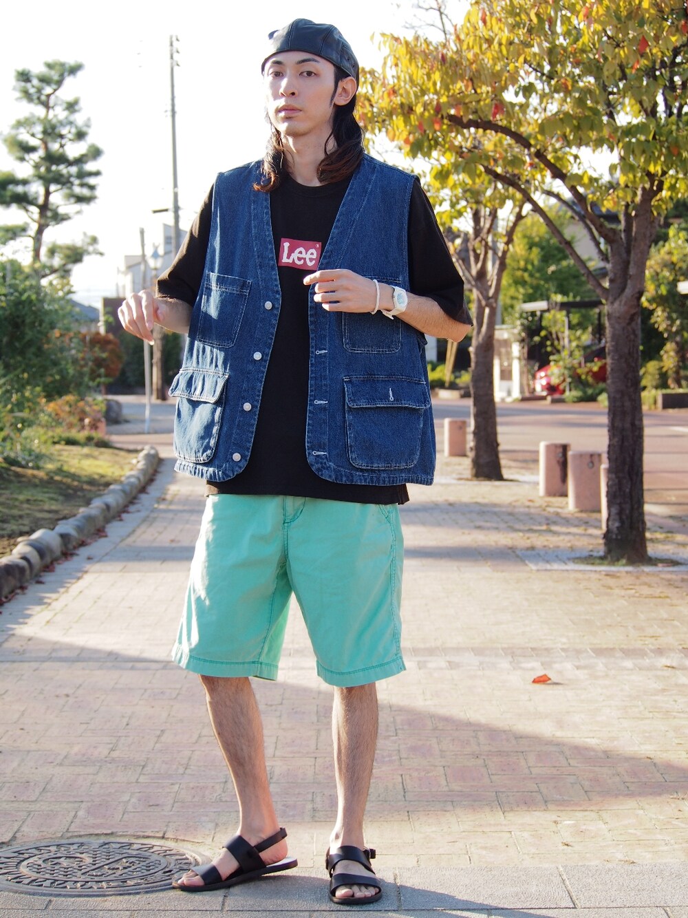 グリーン系のパンツ、ブラック系のサンダル、ブルー系のベストを着用したメンズの冬コーディネートの1枚目の写真