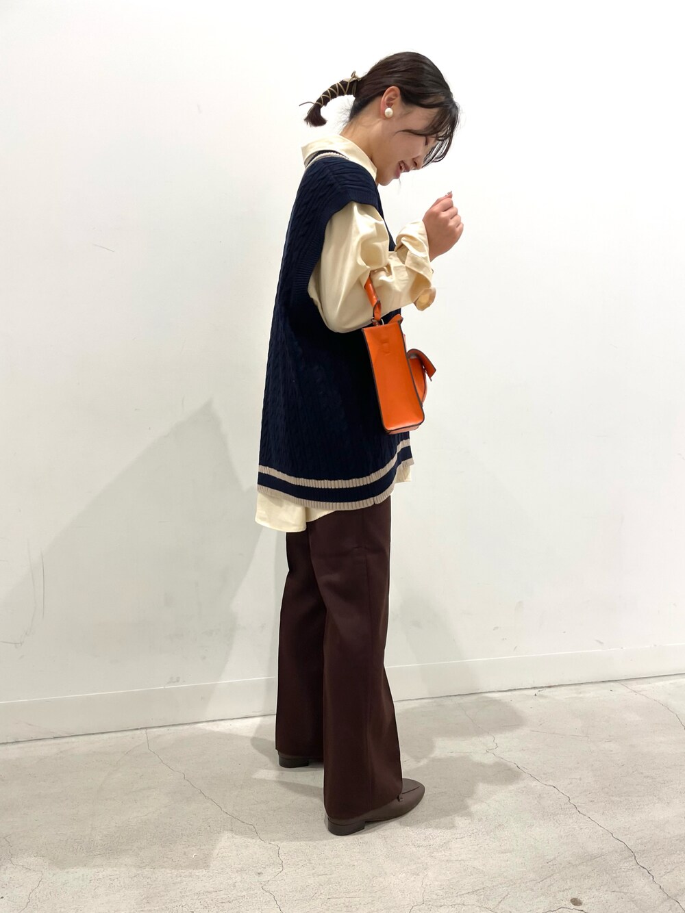 ブルー系のベスト、ベージュ系のシャツ/ブラウス、オレンジ系のショルダーバッグを着用したレディースの夏コーディネートの1枚目の写真