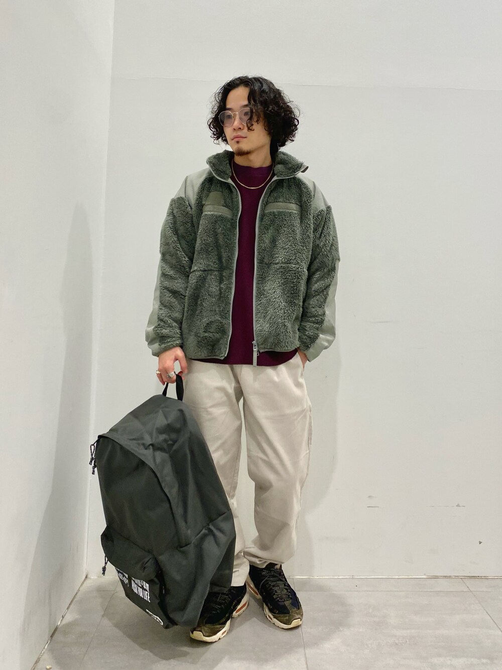 グリーン系のブルゾン、レッド系のTシャツ/カットソー、グレー系のチノパンツを着用したメンズの秋コーディネートの1枚目の写真