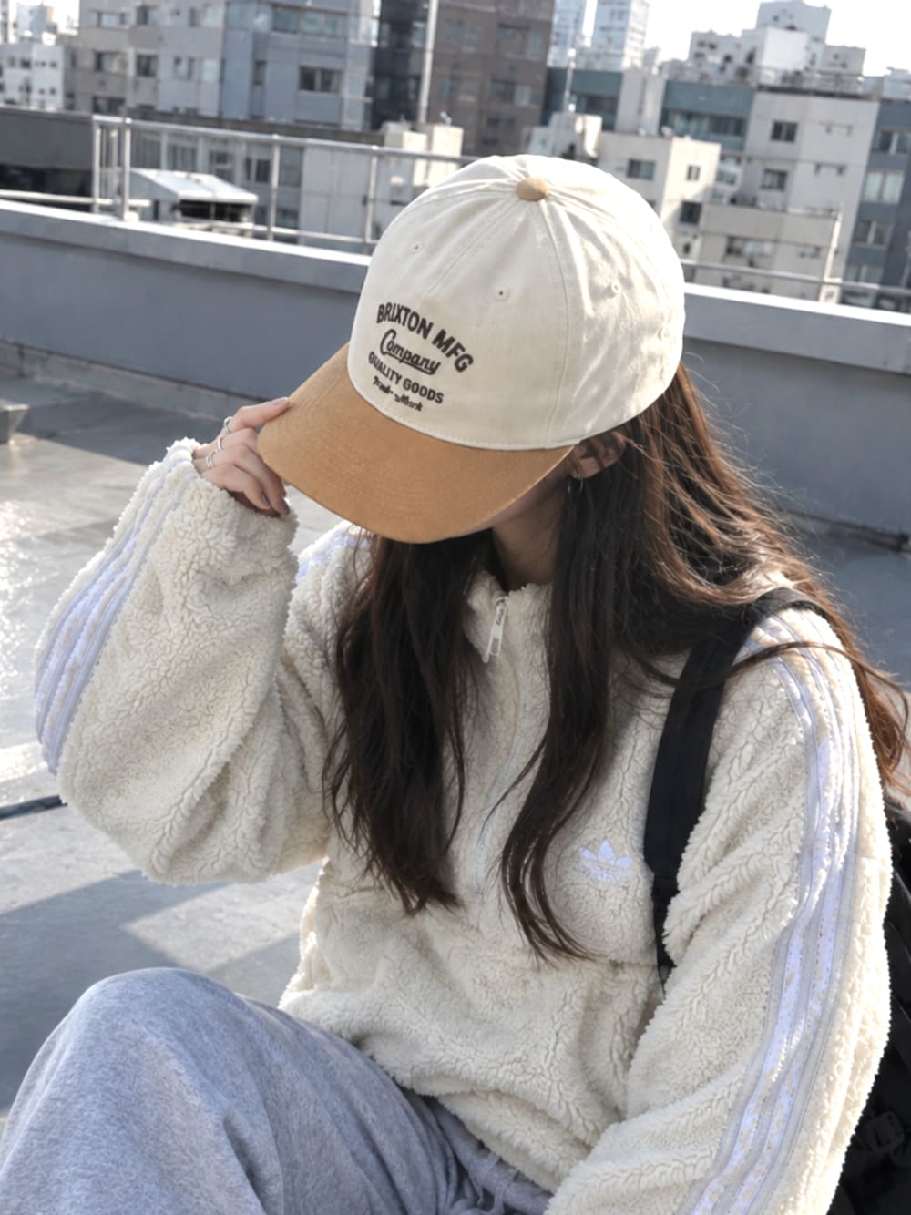 グレー系のスウェットパンツ、ベージュ系のブルゾン、ベージュ系のキャップを着用したレディースの秋コーディネートの1枚目の写真