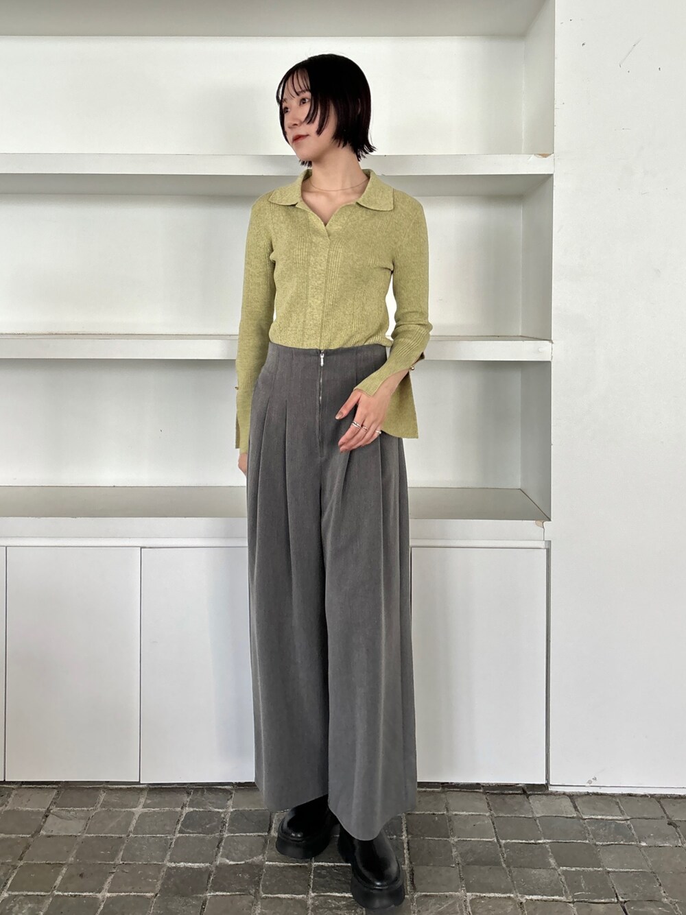 ブラック系のブーツ、グレー系のその他パンツ、グリーン系のニット/セーターを着用したレディースの冬コーディネートの1枚目の写真