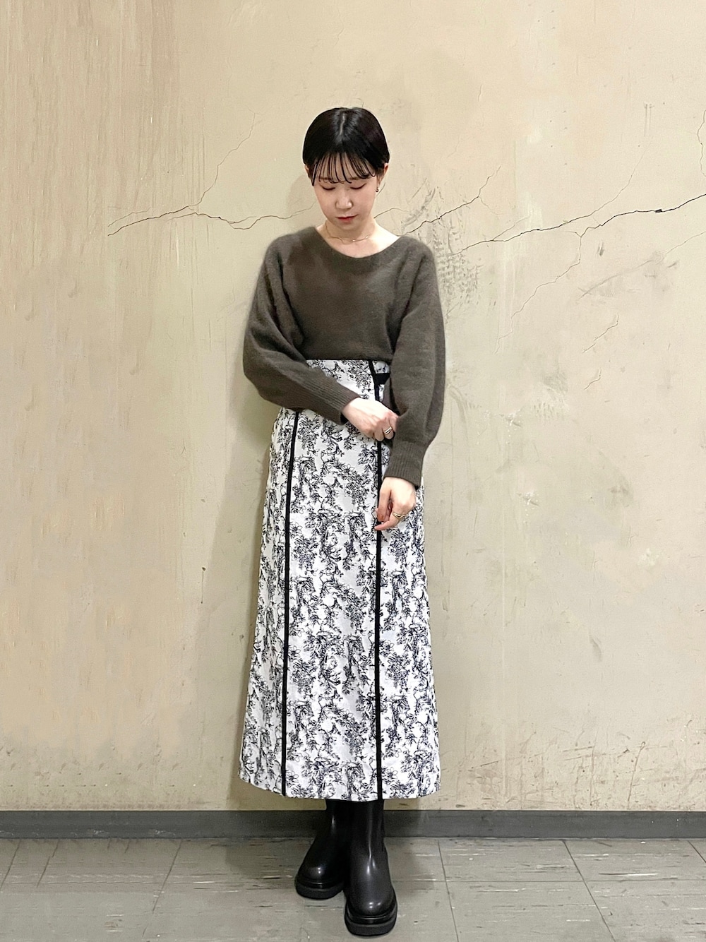 ブラック系のブーツ、ブラウン系のニット/セーター、ブラック系のスカートを着用したレディースの秋コーディネートの1枚目の写真