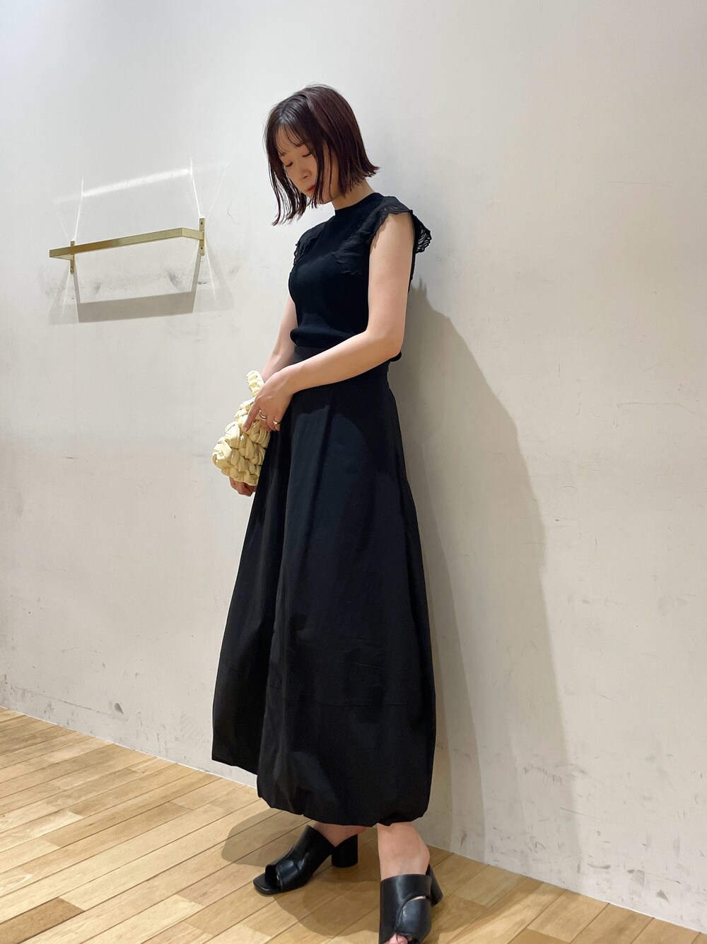 ベージュ系のハンドバッグ、ブラック系のサンダル、ブラック系のニット/セーターを着用したレディースの夏コーディネートの1枚目の写真