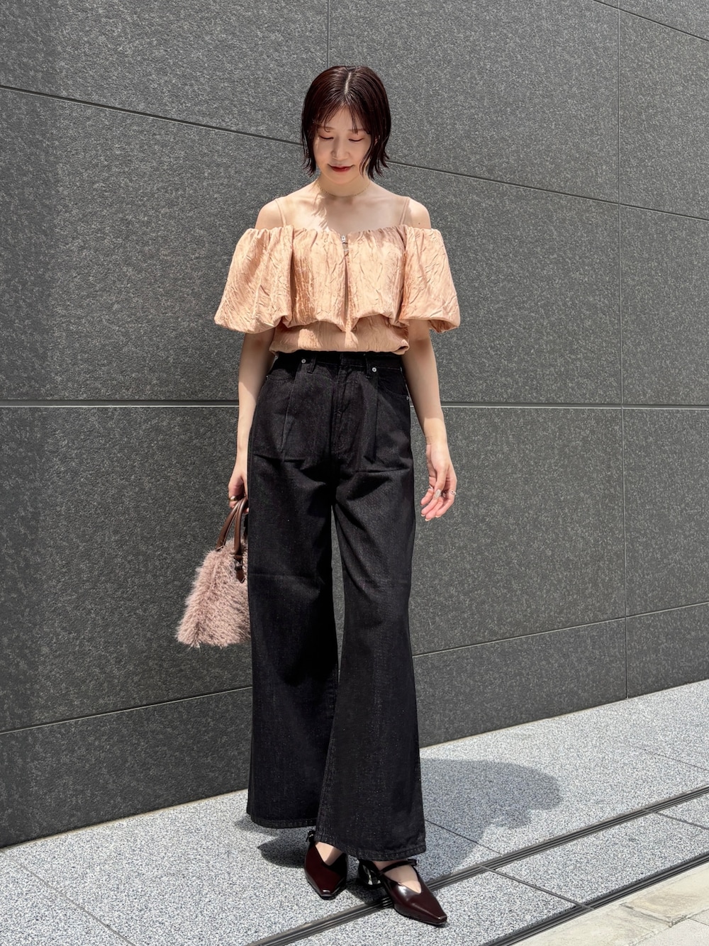 ブラック系のデニムパンツ、ブラウン系のパンプス、ブラウン系のボストンバッグを着用したレディースの夏コーディネートの1枚目の写真