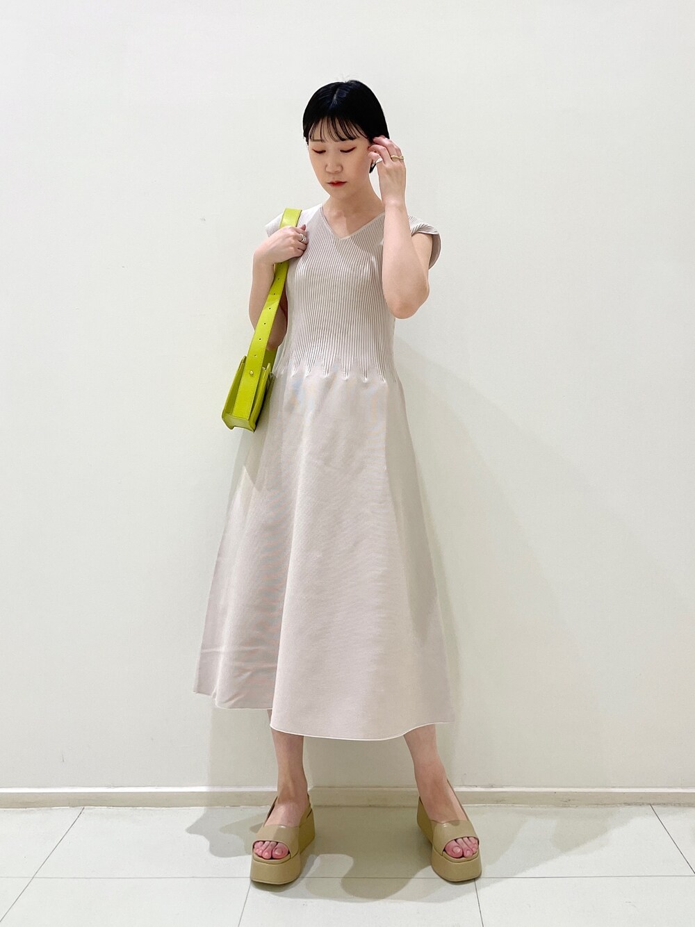 ベージュ系のサンダル、グリーン系のショルダーバッグ、グレー系のワンピースを着用したレディースの春コーディネートの1枚目の写真