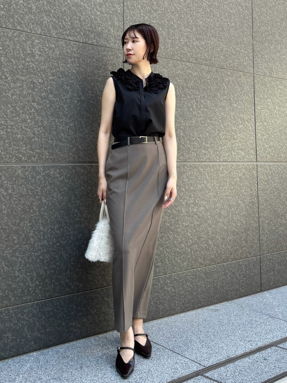 グレー系のスカート、ホワイト系のボストンバッグ、ブラウン系のパンプスを着用したレディースの夏コーディネートの1枚目の写真