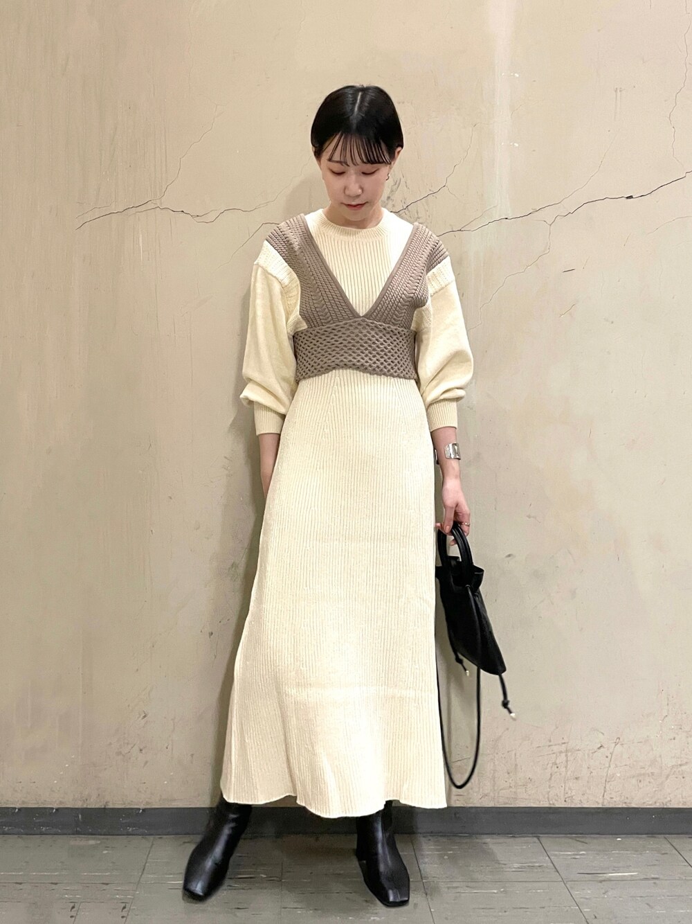 ホワイト系のワンピース、ブラック系のブーツ、ブラック系のハンドバッグを着用したレディースの秋コーディネートの1枚目の写真