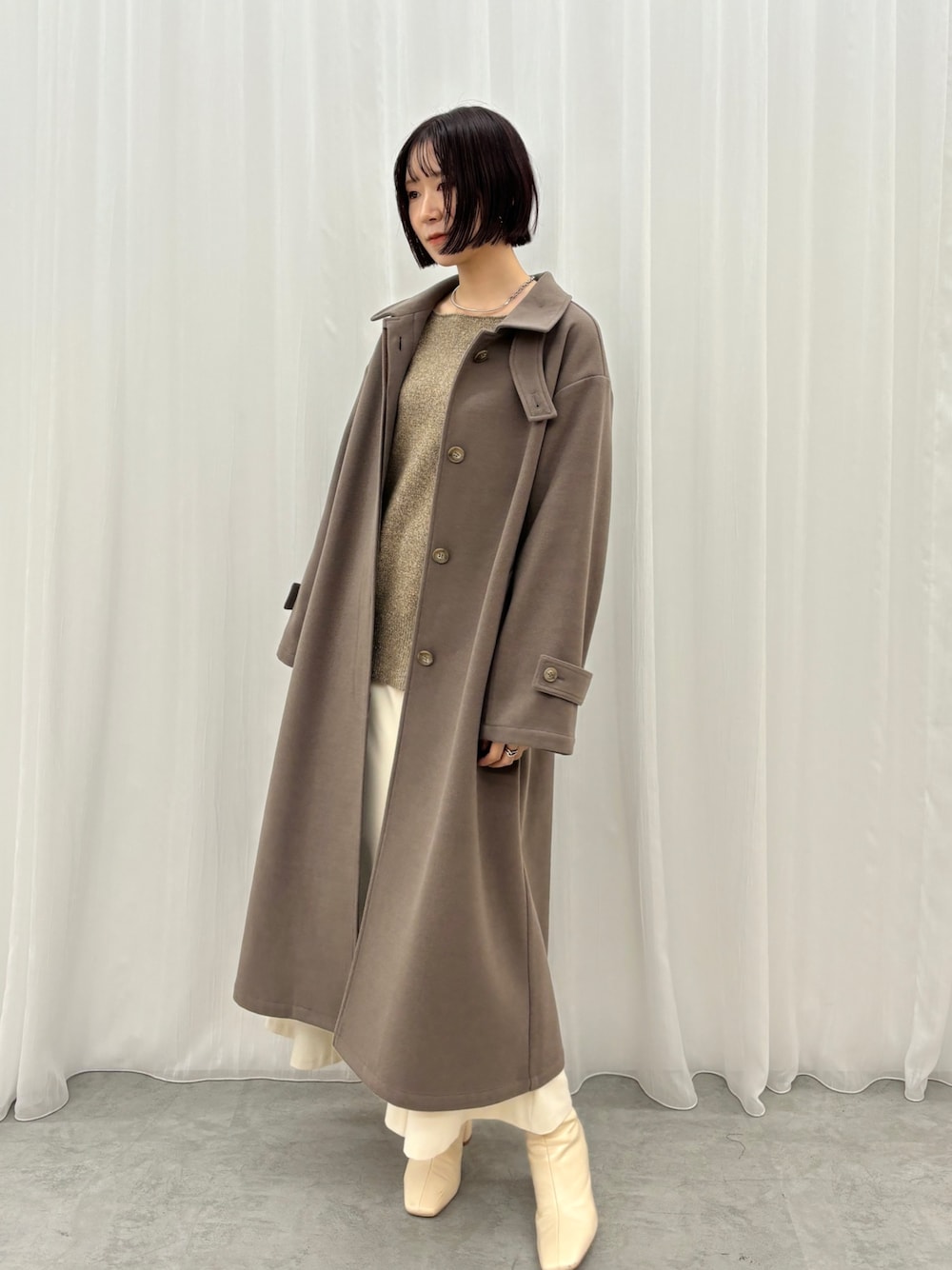 ホワイト系のスカート、ブラウン系のニット/セーター、ブラウン系のステンカラーコートを着用したレディースの秋コーディネートの1枚目の写真