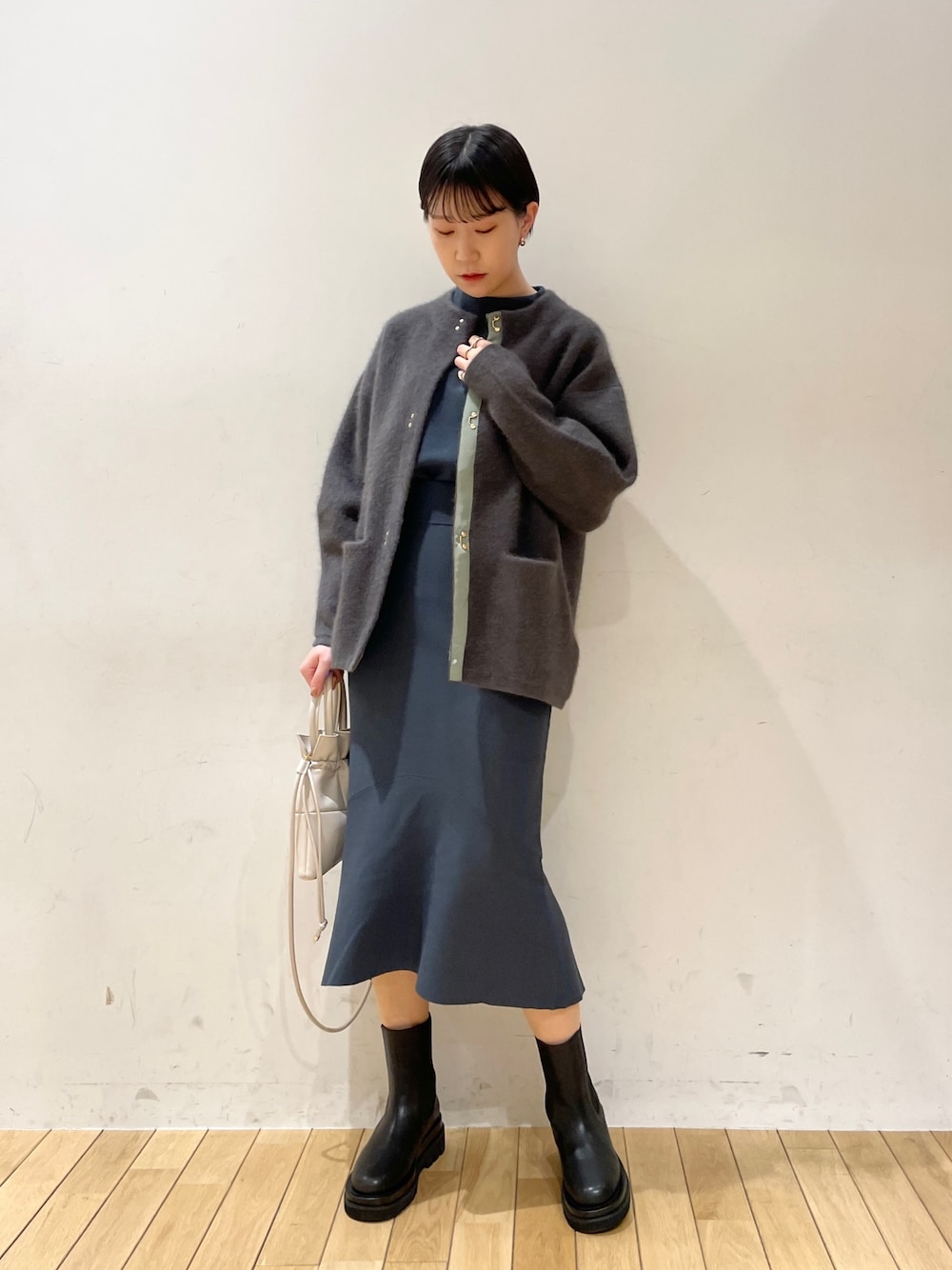 グレー系のカーディガン/ボレロ、グリーン系のニット/セーター、グリーン系のスカートを着用したレディースの冬コーディネートの1枚目の写真