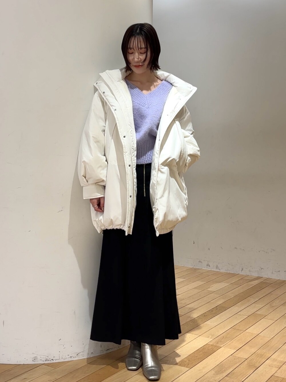 ブラック系のスカート、パープル系のニット/セーター、ホワイト系のダウンジャケット/コートを着用したレディースの冬コーディネートの1枚目の写真