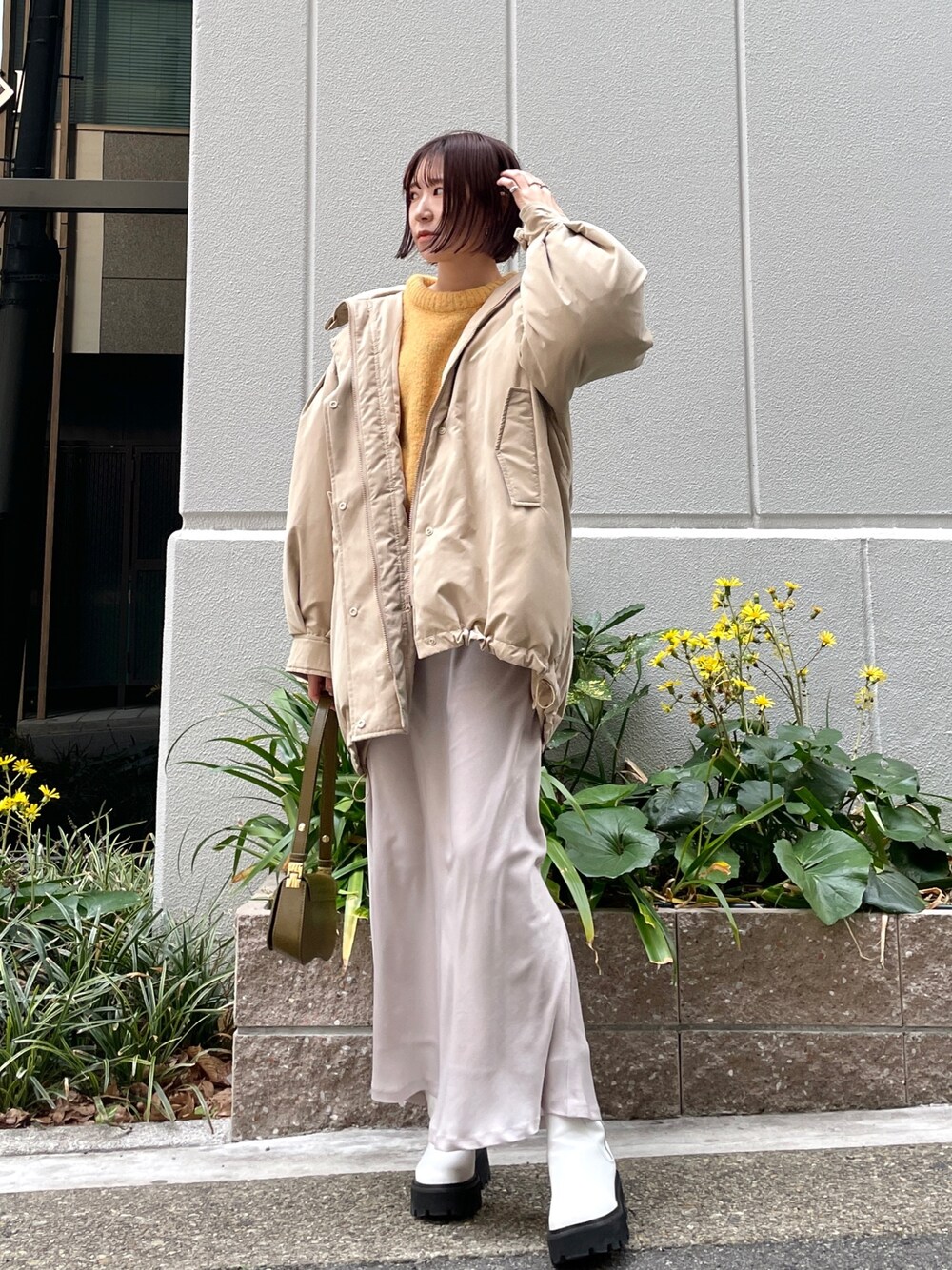 ベージュ系のダウンジャケット/コート、ホワイト系のスカート、ブラウン系のショルダーバッグを着用したレディースの冬コーディネートの1枚目の写真