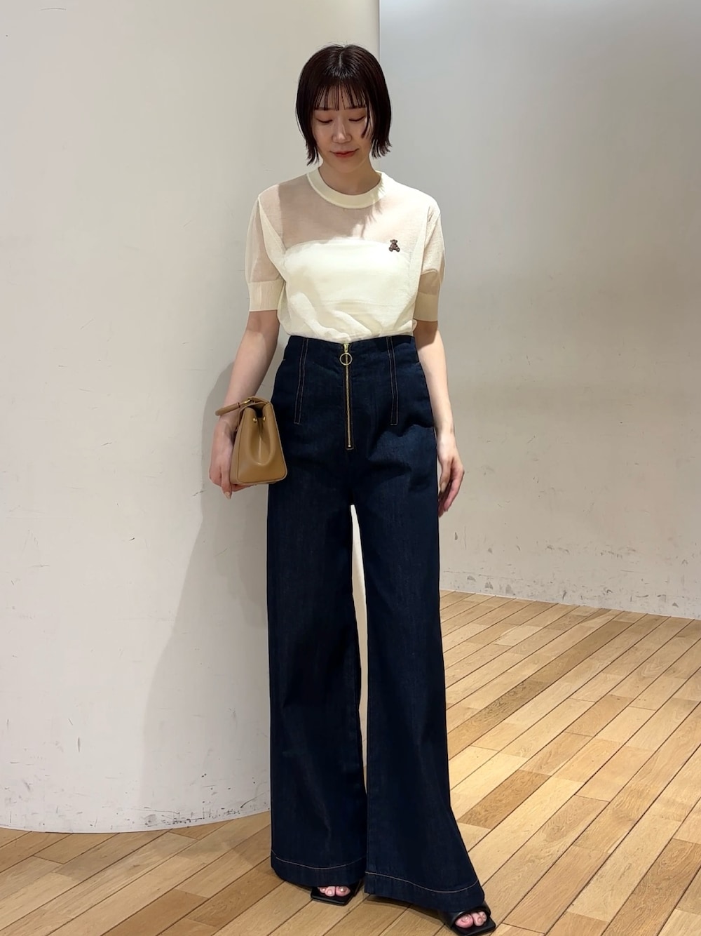 ブルー系のデニムパンツ、イエロー系のハンドバッグ、ブラック系のサンダルを着用したレディースの春コーディネートの1枚目の写真