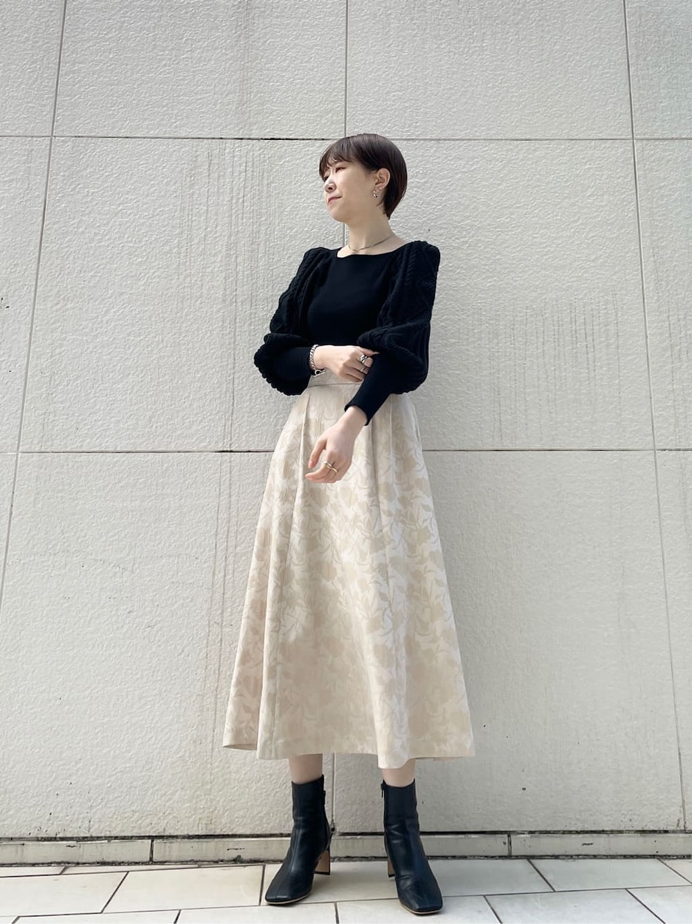 ブラック系のその他シューズ、ベージュ系のスカート、ブラック系のニット/セーターを着用したレディースの冬コーディネートの1枚目の写真