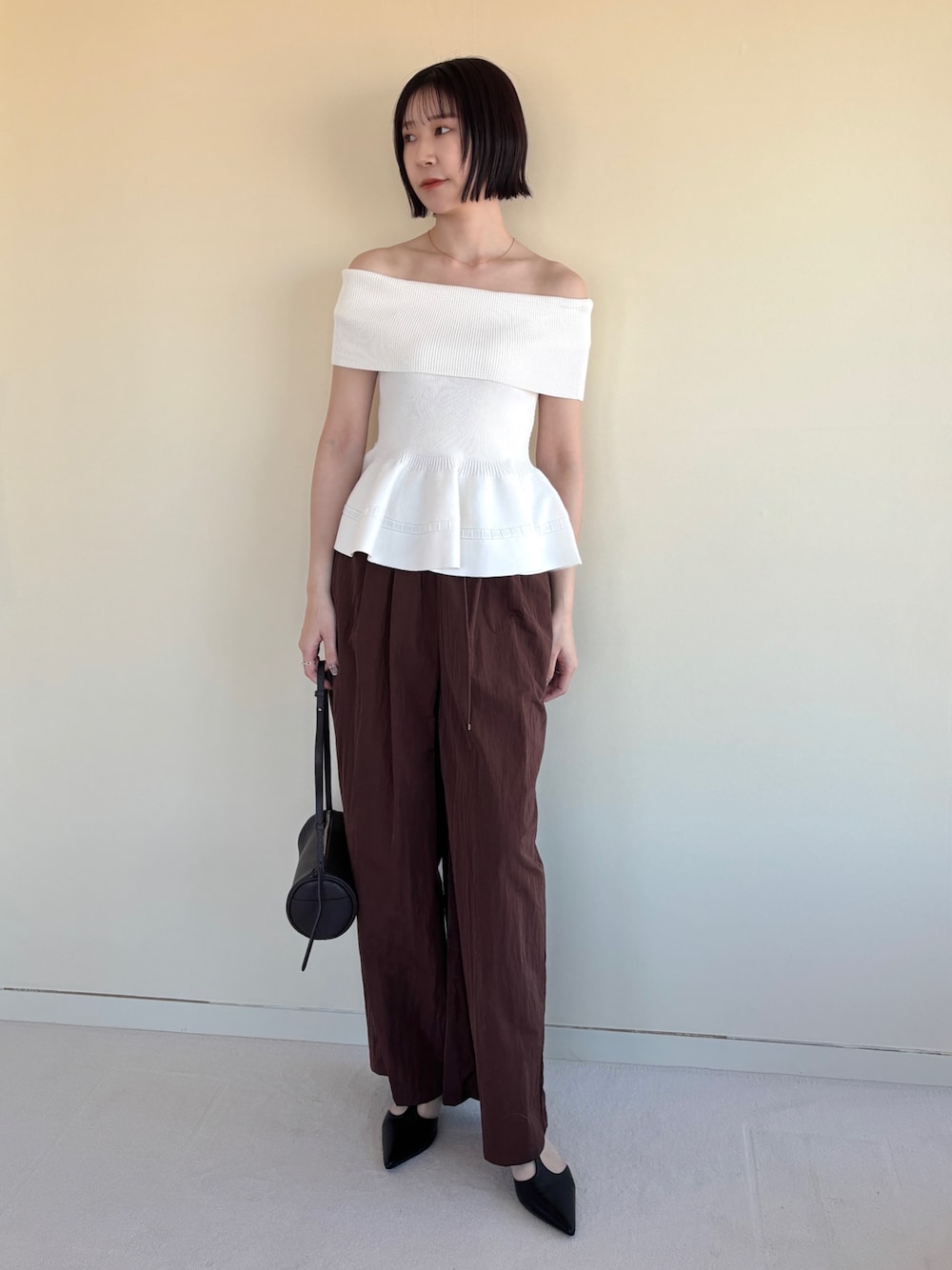ブラウン系のその他パンツ、ブラック系のパンプス、ホワイト系のニット/セーターを着用したレディースの春コーディネートの1枚目の写真