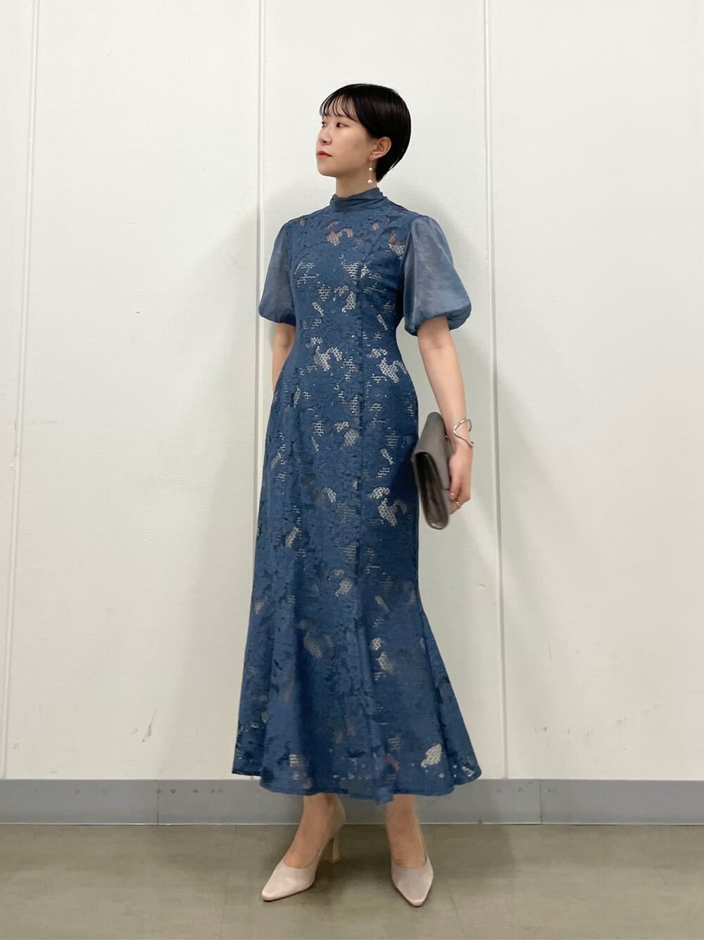 シルバー系のクラッチバッグ、ベージュ系のパンプス、ブルー系のドレスを着用したレディースの夏コーディネートの1枚目の写真