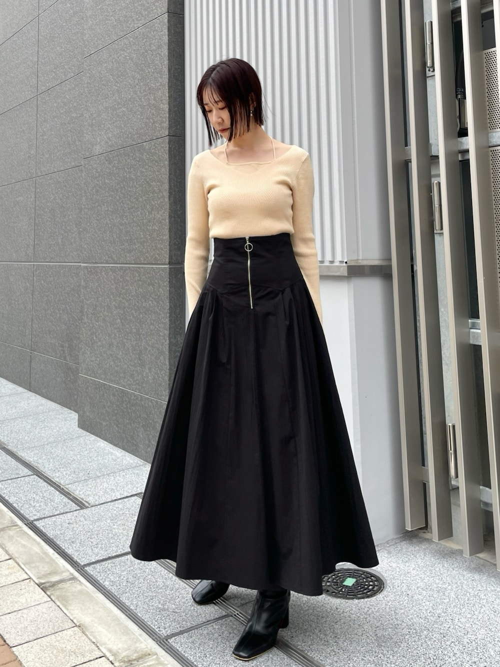 ブラック系のブーツ、ホワイト系のニット/セーター、ブラック系のスカートを着用したレディースの冬コーディネートの1枚目の写真