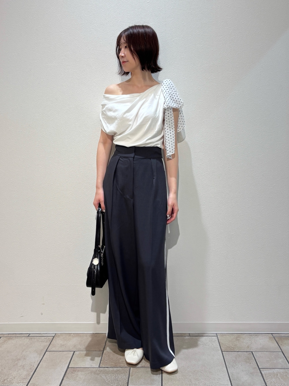グレー系のその他パンツ、ホワイト系のサンダル、ブラック系のハンドバッグを着用したレディースの夏コーディネートの1枚目の写真