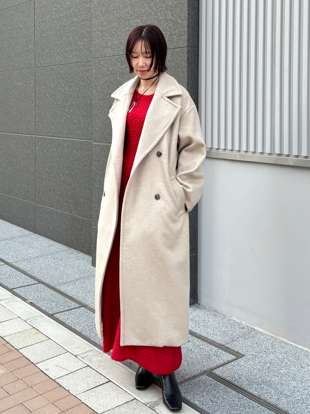 レッド系のワンピース、ホワイト系のチェスターコートを着用したレディースの冬コーディネートの1枚目の写真