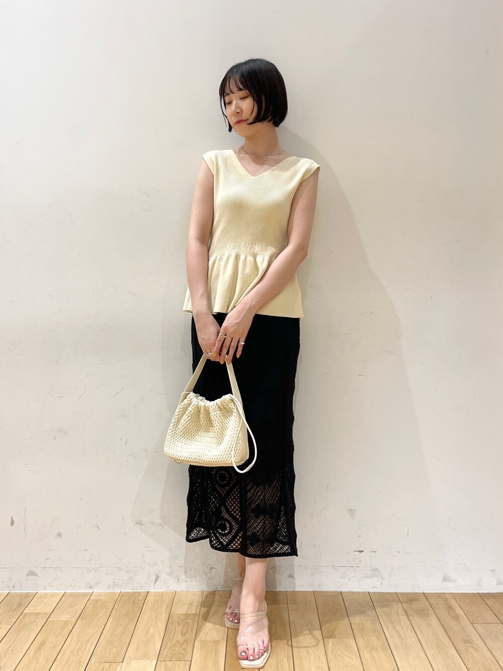ベージュ系のハンドバッグ、ホワイト系のニット/セーター、ブラック系のスカートを着用したレディースの夏コーディネートの1枚目の写真
