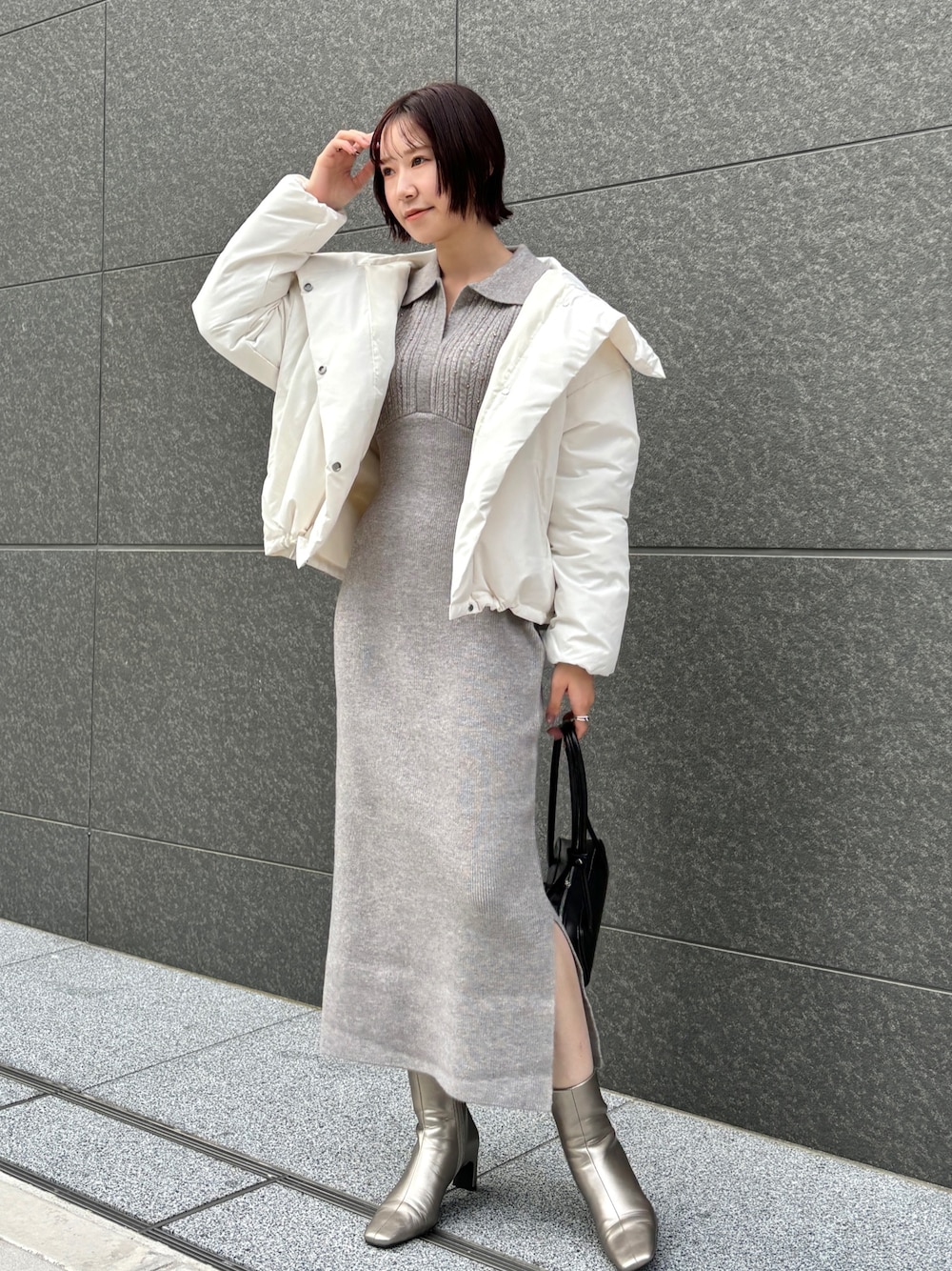 グレー系のワンピース、ホワイト系のダウンジャケット/コート、ブラック系のショルダーバッグを着用したレディースの秋コーディネートの1枚目の写真