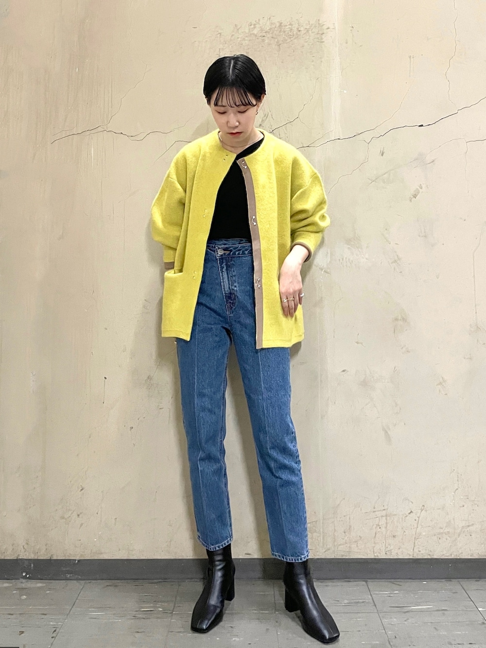 ブラック系のニット/セーター、イエロー系のカーディガン/ボレロ、ブルー系のデニムパンツを着用したレディースの秋コーディネートの1枚目の写真