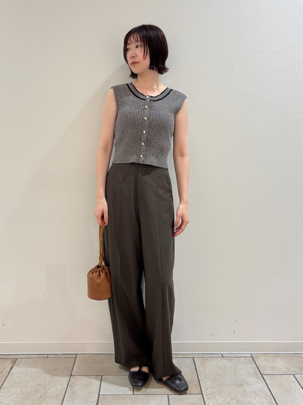 ブラウン系のその他パンツ、グレー系のニット/セーター、イエロー系のハンドバッグを着用したレディースの夏コーディネートの1枚目の写真