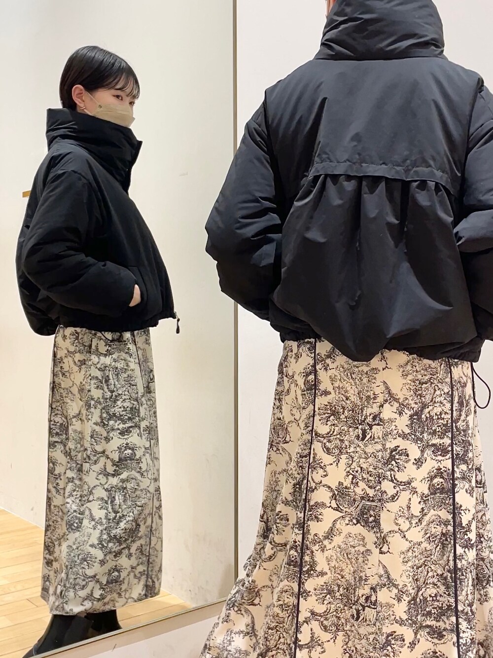 ブラック系のダウンジャケット/コート、ホワイト系のワンピース、ブラック系のブーツを着用したレディースの冬コーディネートの1枚目の写真