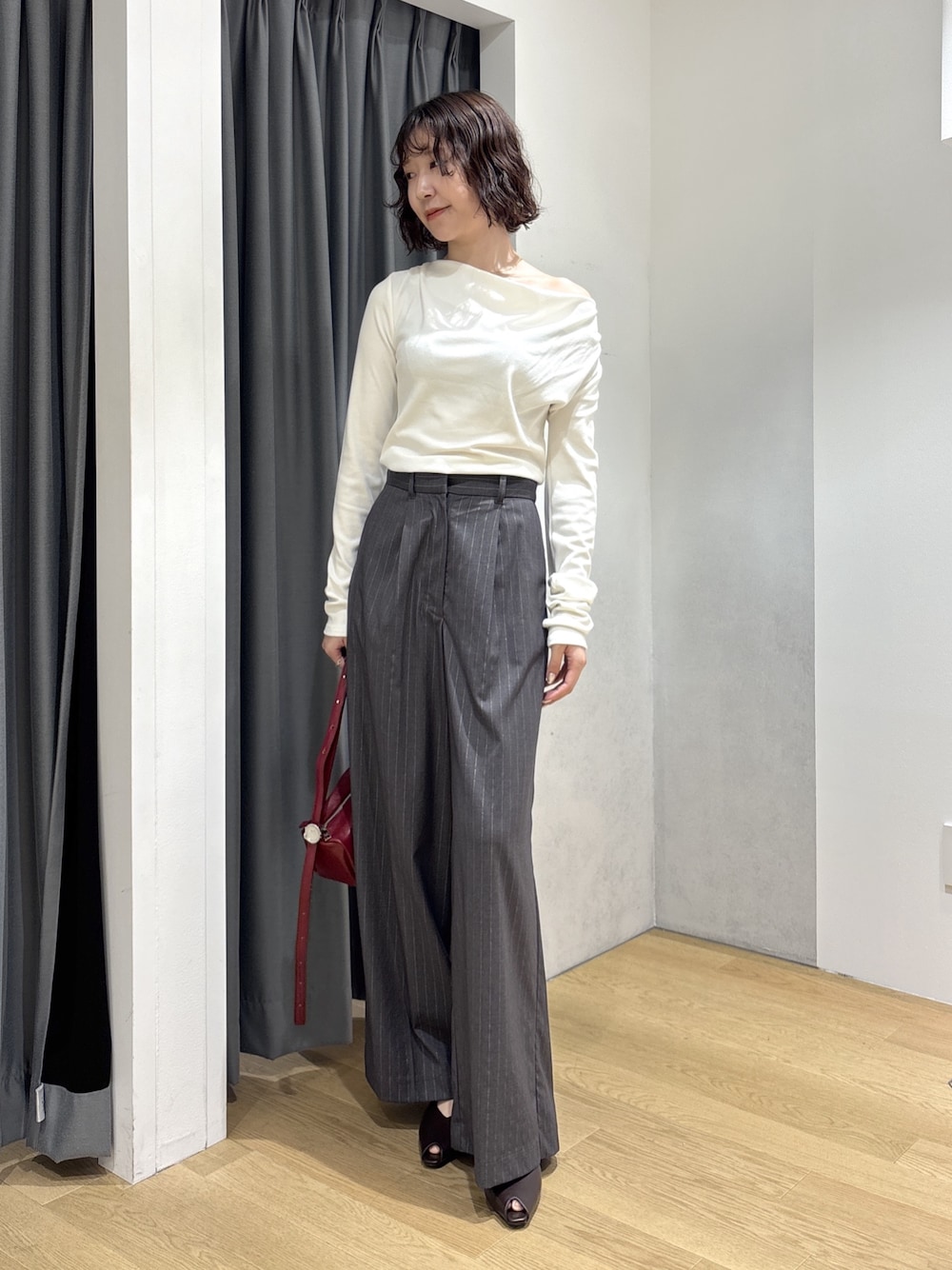 グレー系のその他パンツ、ホワイト系のニット/セーター、レッド系のハンドバッグを着用したレディースの秋コーディネートの1枚目の写真