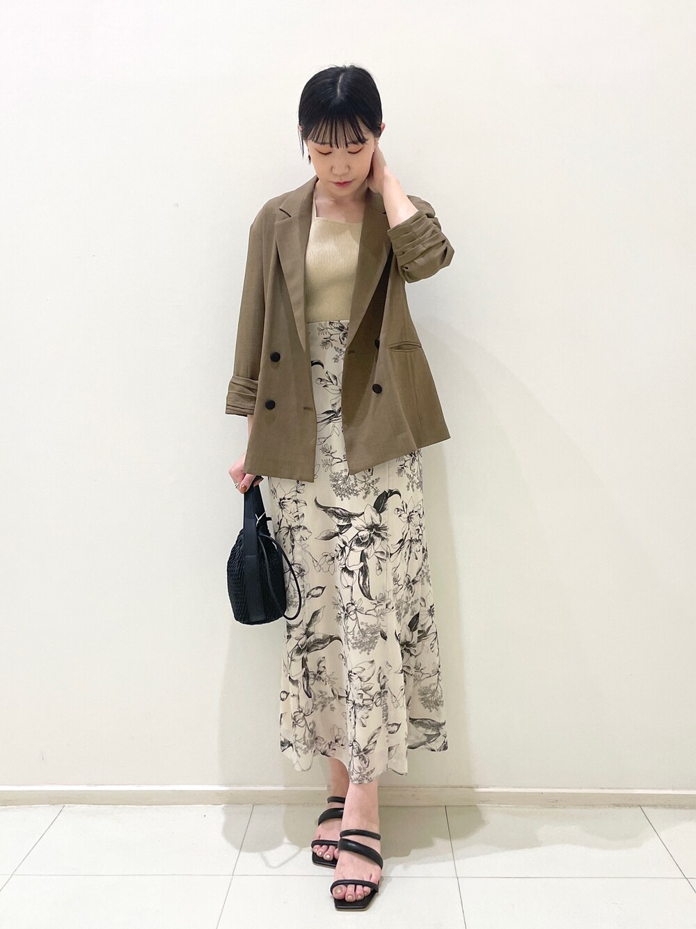 ブラウン系のテーラードジャケット、ベージュ系のニット/セーター、ホワイト系のスカートを着用したレディースの春コーディネートの1枚目の写真