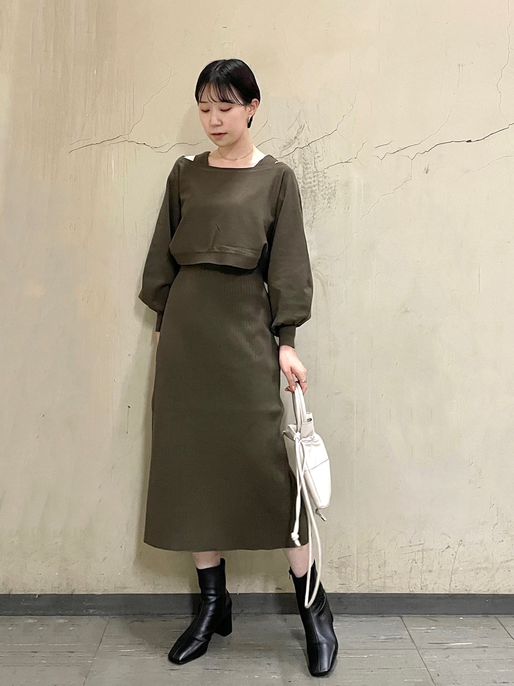 ブラウン系のワンピース、ブラック系のブーツ、ホワイト系のハンドバッグを着用したレディースの秋コーディネートの1枚目の写真