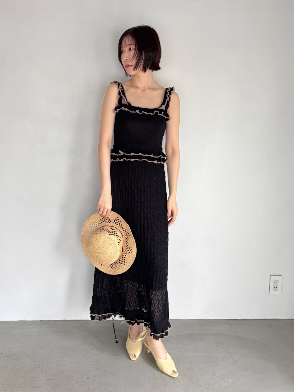 ブラック系のワンピース、イエロー系のパンプスを着用したレディースの夏コーディネートの1枚目の写真