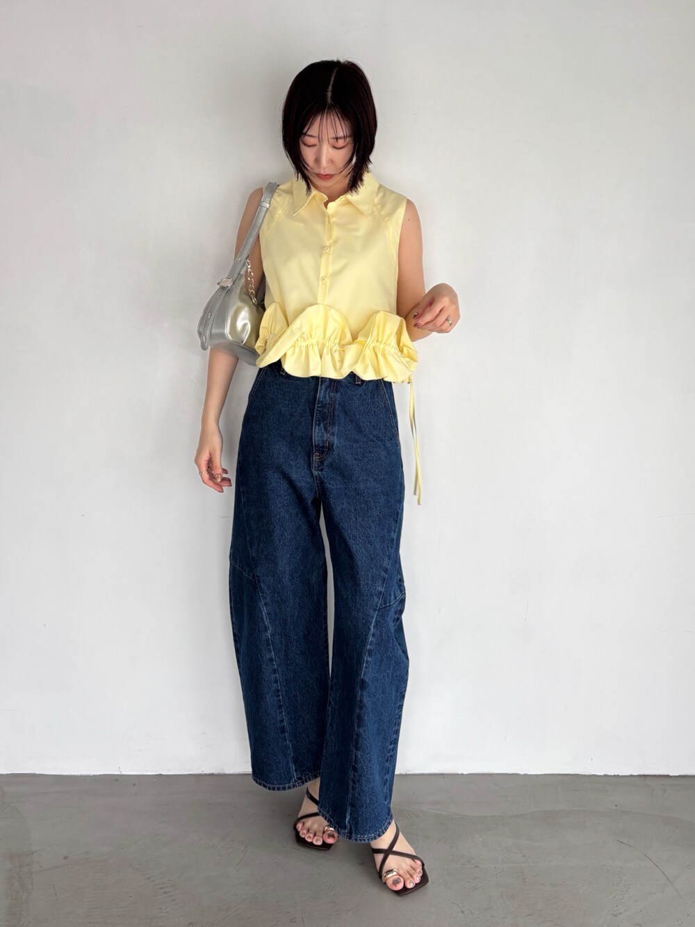 ブルー系のデニムパンツ、イエロー系のシャツ/ブラウス、シルバー系のハンドバッグを着用したレディースの夏コーディネートの1枚目の写真