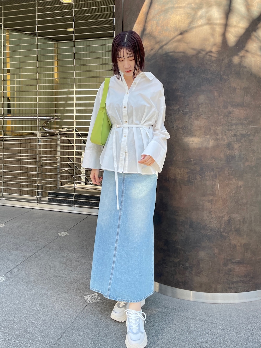 ホワイト系のシャツ/ブラウス、グリーン系のデニムスカート、ホワイト系のスニーカーを着用したレディースの春コーディネートの1枚目の写真