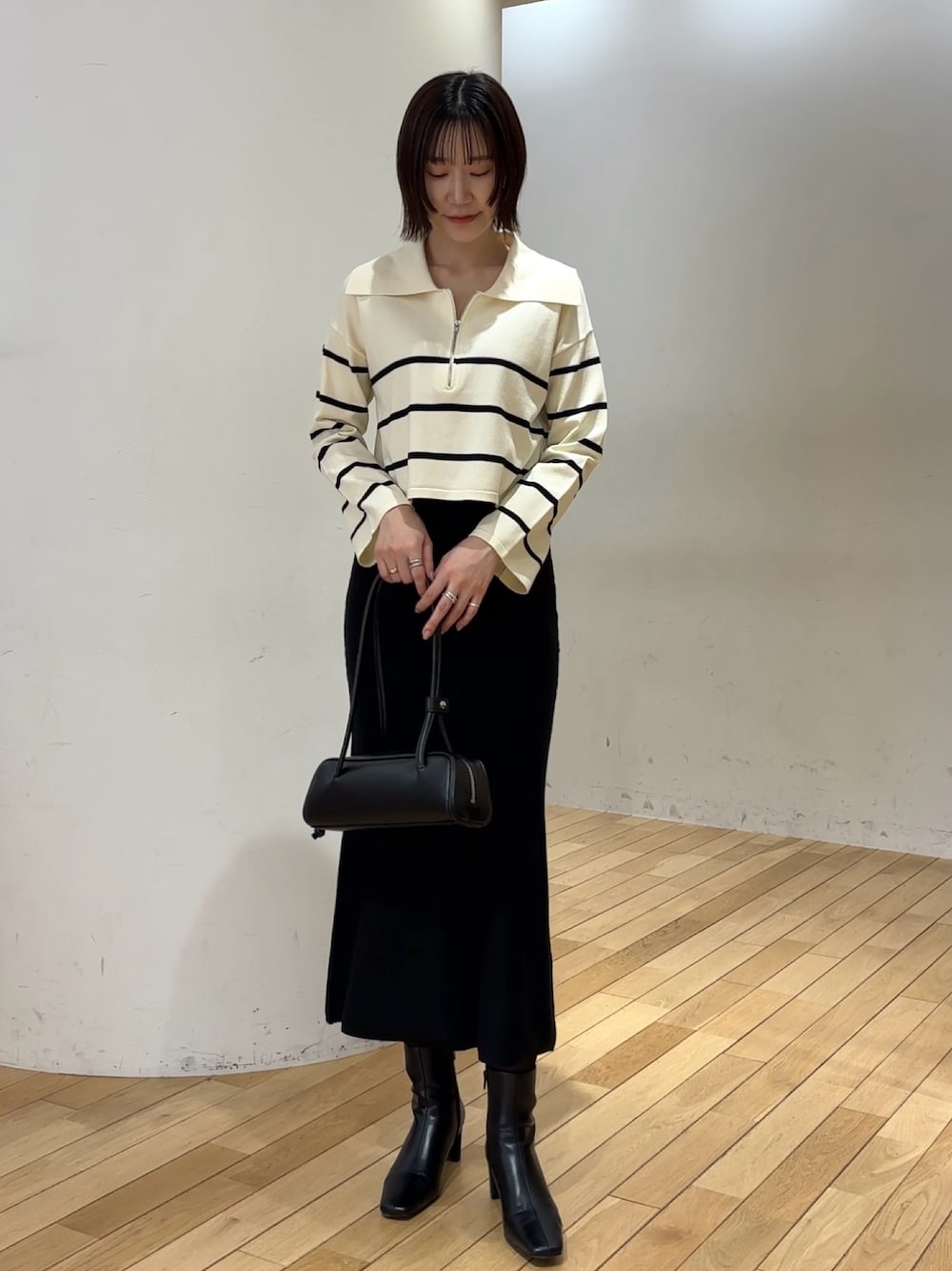 ホワイト系のニット/セーター、ブラック系のスカート、ブラック系のブーツを着用したレディースの冬コーディネートの1枚目の写真
