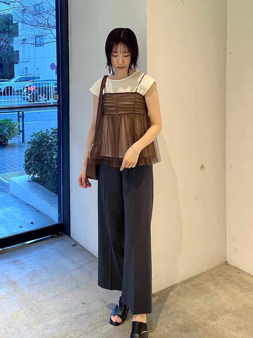 ブラウン系のTシャツ/カットソー、ブルー系のスラックス、ブラック系のサンダルを着用したレディースの春コーディネートの1枚目の写真