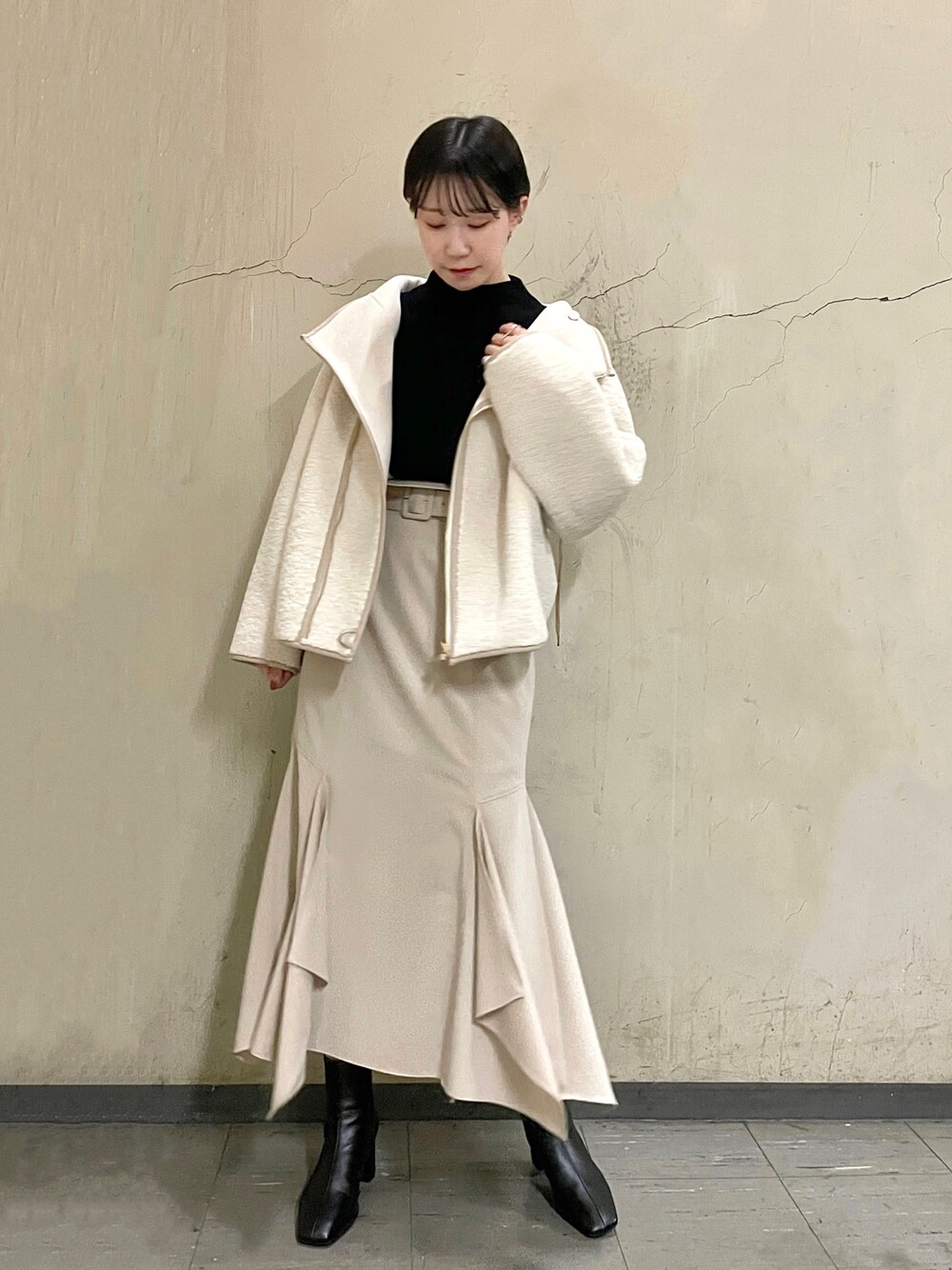 ホワイト系のブルゾン、ブラック系のブーツ、ベージュ系のスカートを着用したレディースの秋コーディネートの1枚目の写真